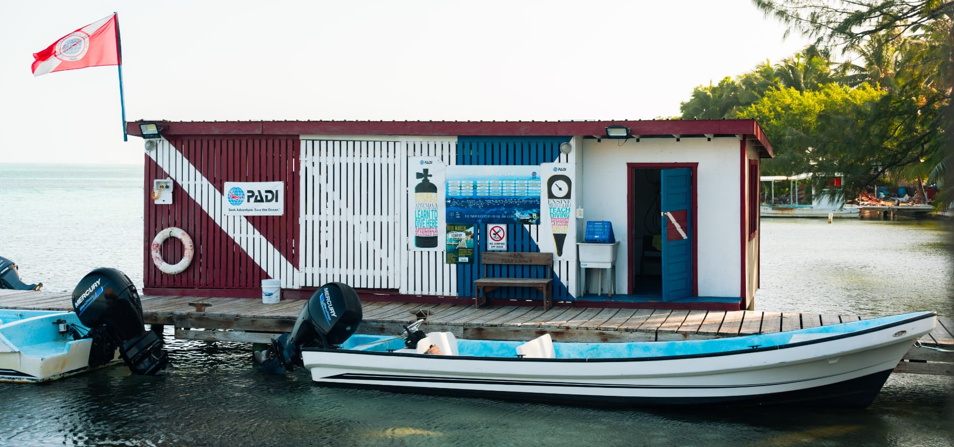 A colorful dive shop with a PADI sign and boats docked nearby.