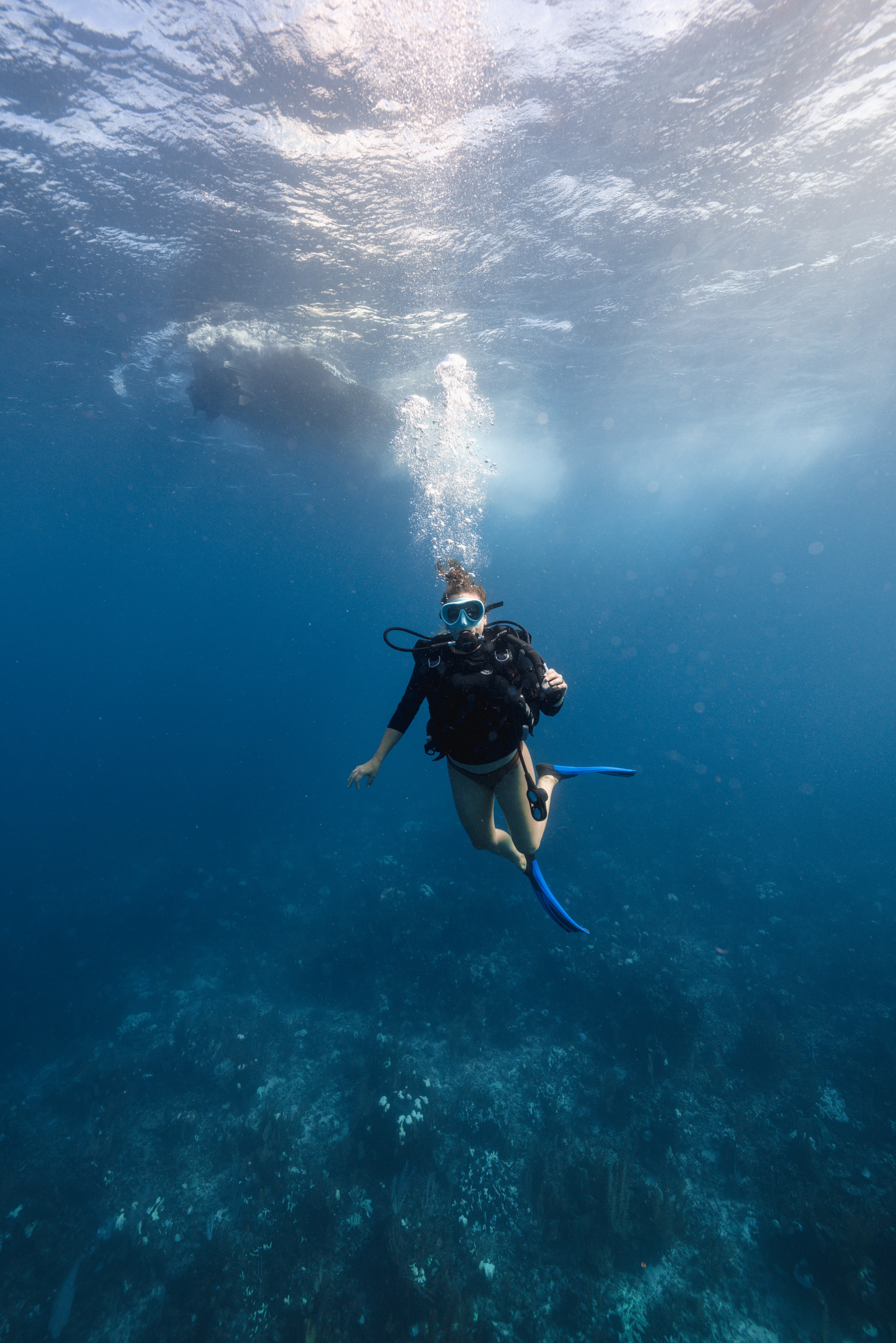 A scuba diver swims underwater in clear blue water.