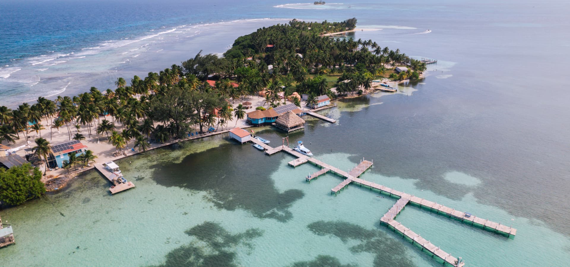 Aerial view of a tropical island featuring palm trees, docks, and clear turquoise waters.