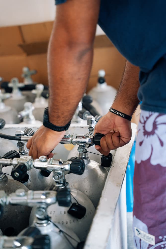 A person adjusts the valve on a metal gas cylinder.