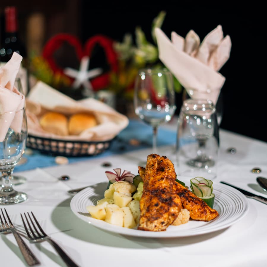 A plate of grilled fish served with seasoned potatoes and vegetables, set on an elegantly prepared dining table.