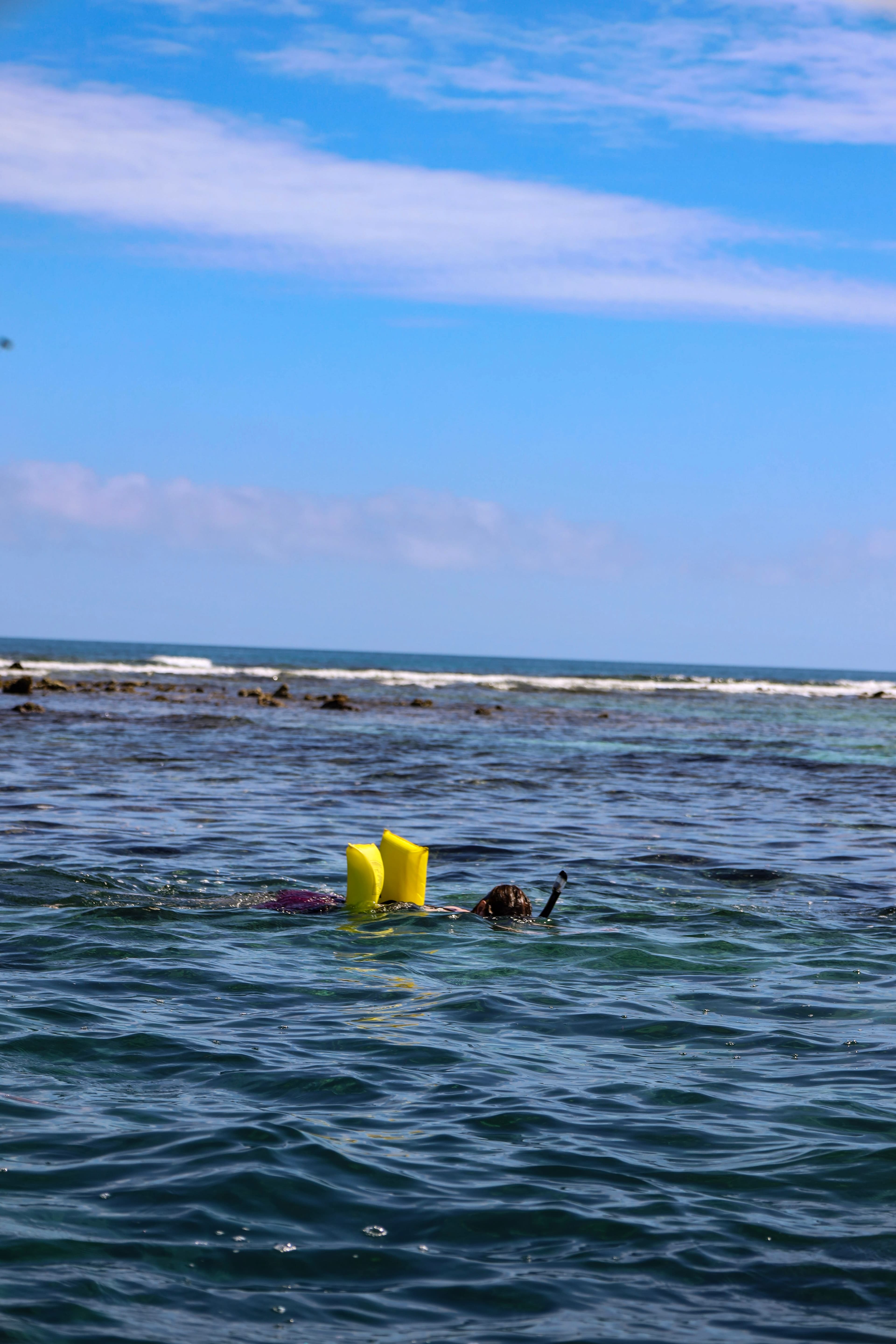 A person snorkeling in the ocean with yellow fins.