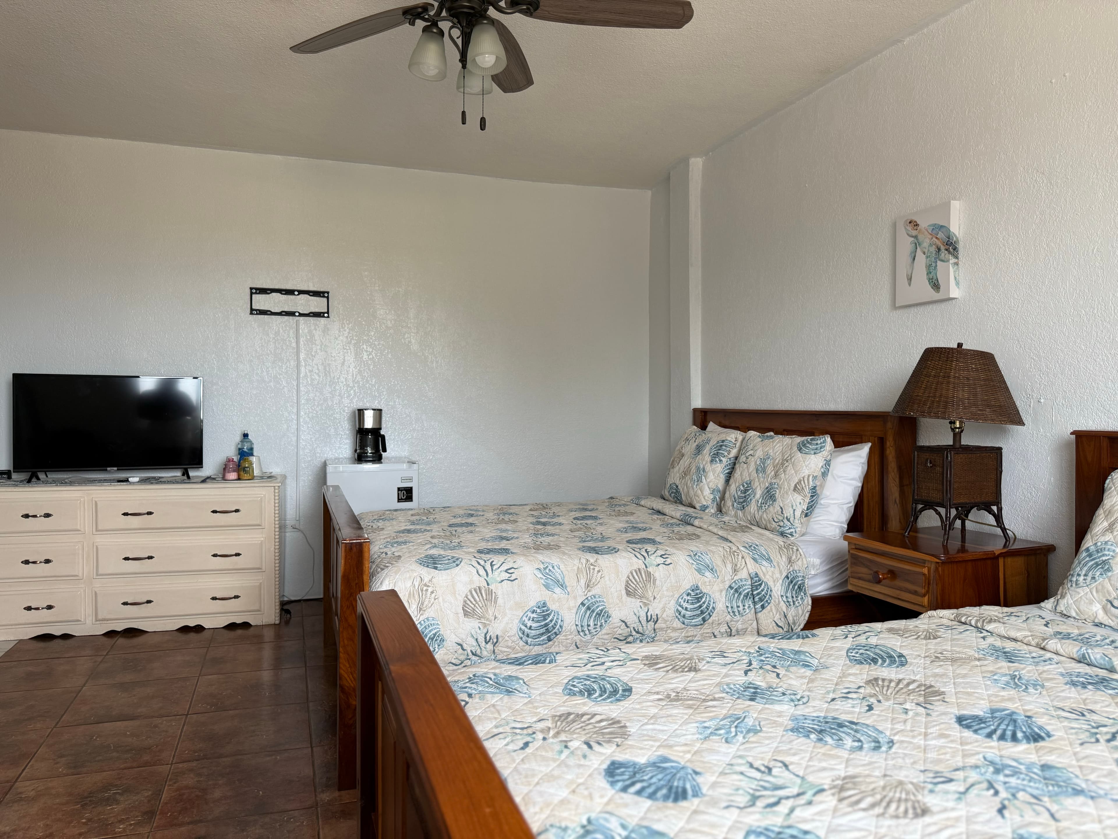A cozy hotel room featuring two beds, a television, a coffee maker, and a decorative lamp.
