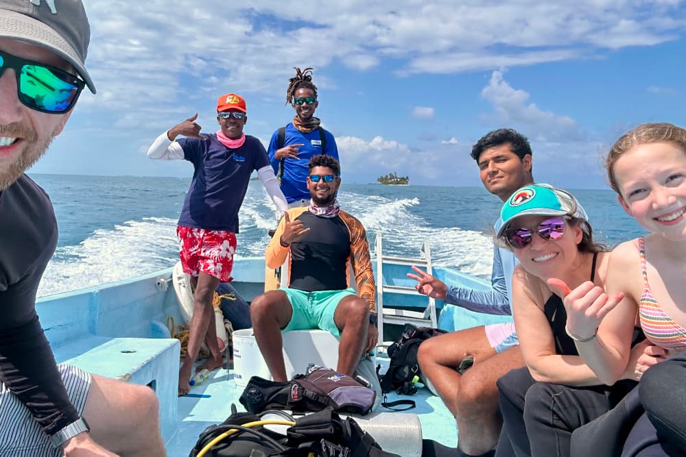 A group of six people is happily posing on a boat while enjoying a sunny day at sea.