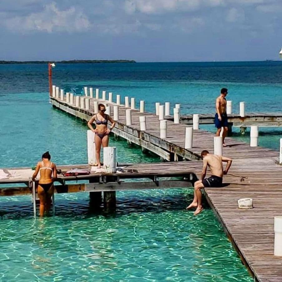 Several people on a dock getting ready to go swimming.