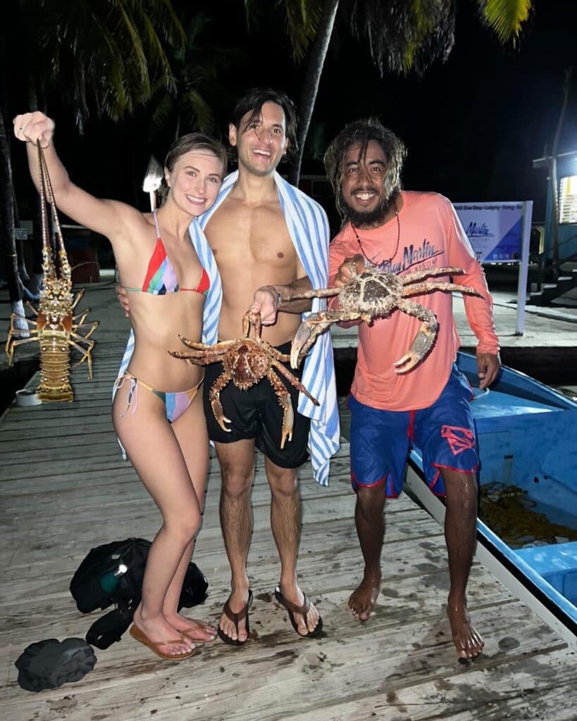Three people holding freshly caught lobster and crab